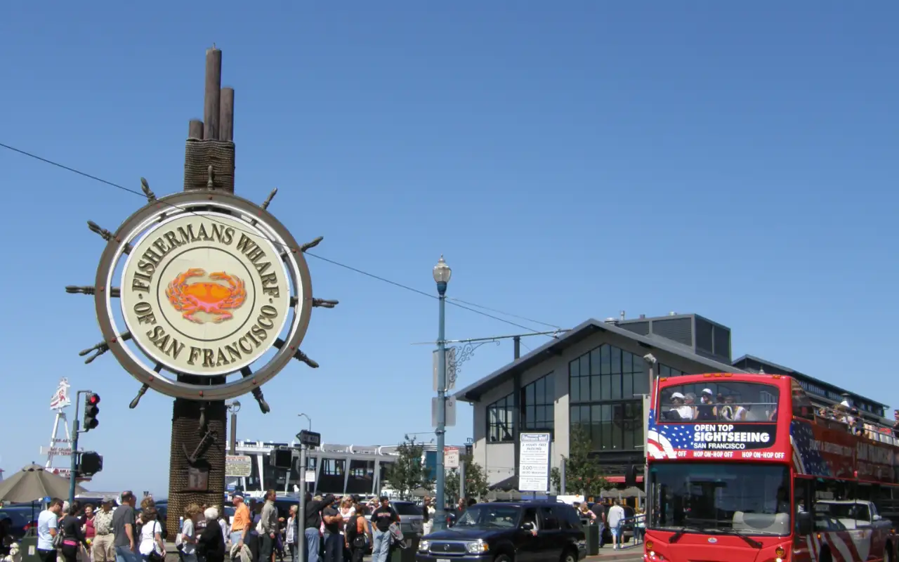 A bustling scene at Fishermans Wharf with boats docked, tourists exploring the area, and seafood vendors serving fresh catch.