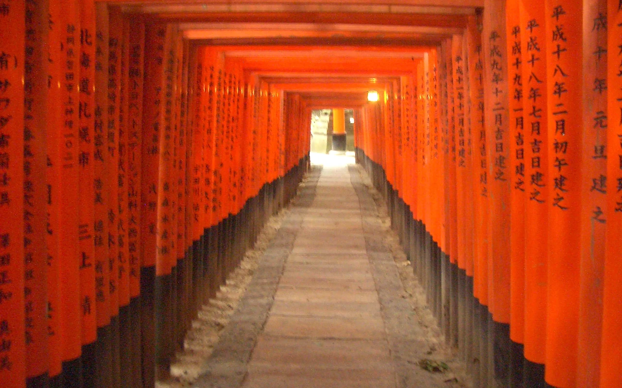 A stunning view of Fushimi Inari Taisha, the iconic Japanese Shinto shrine with vibrant orange torii gates and lush greenery surrounding it