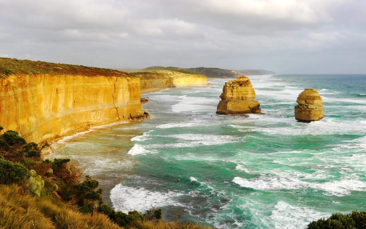 Scenic view of the Great Ocean Road, winding along the coastline with turquoise waters and lush greenery