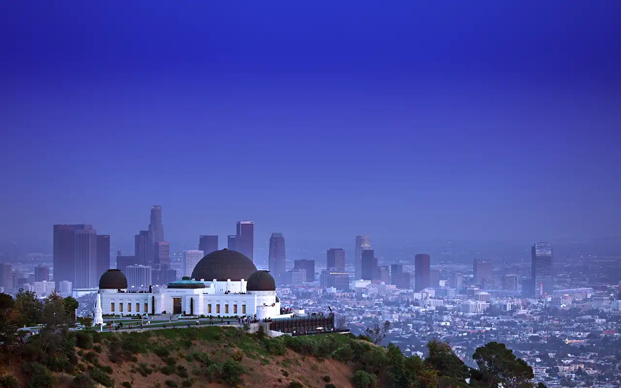 A stunning view of Griffith Observatory, an iconic Los Angeles landmark, situated atop a hill with a beautiful cityscape backdrop