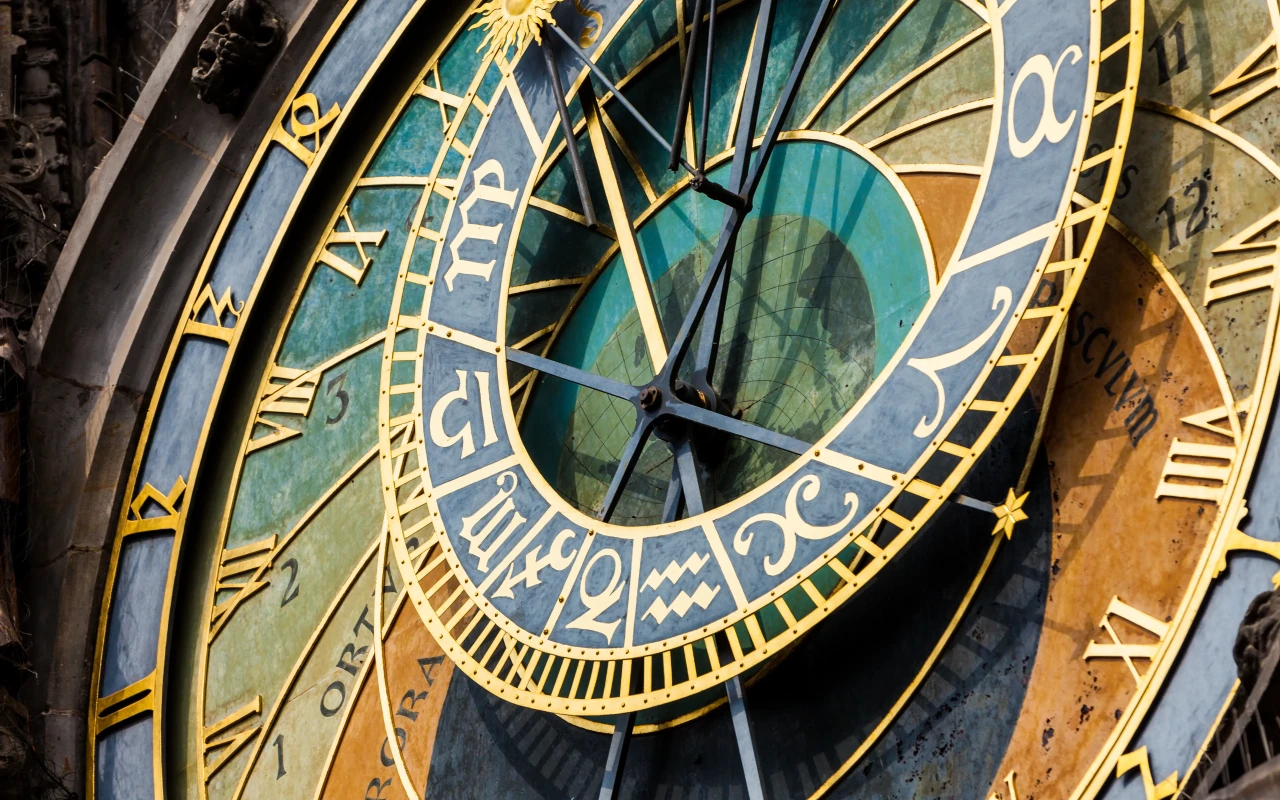 Person examining and learning how to read the Prague Astronomical Clock, a medieval clock tower with detailed astronomical dials and figures.