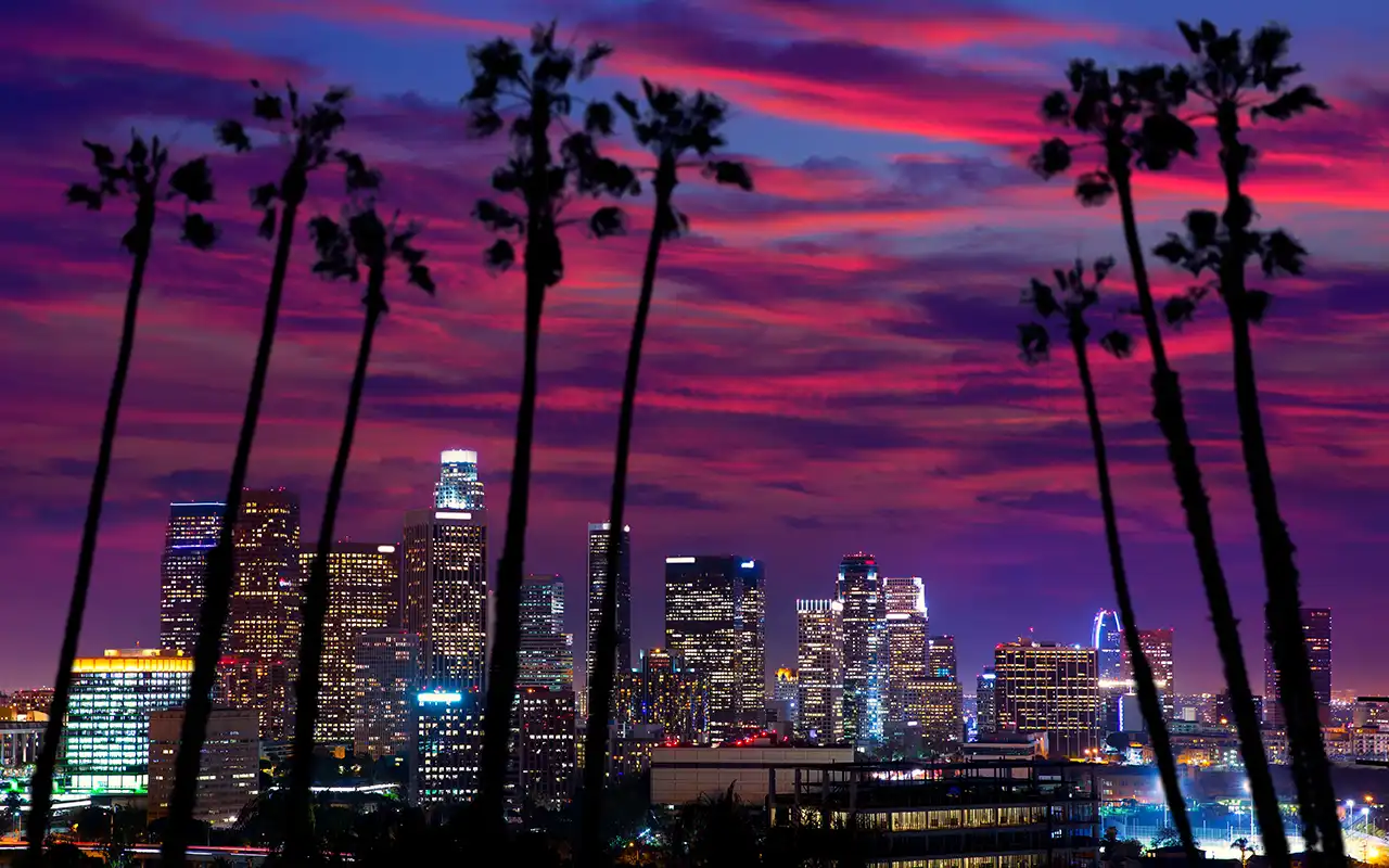 Aerial view of the Los Angeles skyline with palm trees and mountains in the background
