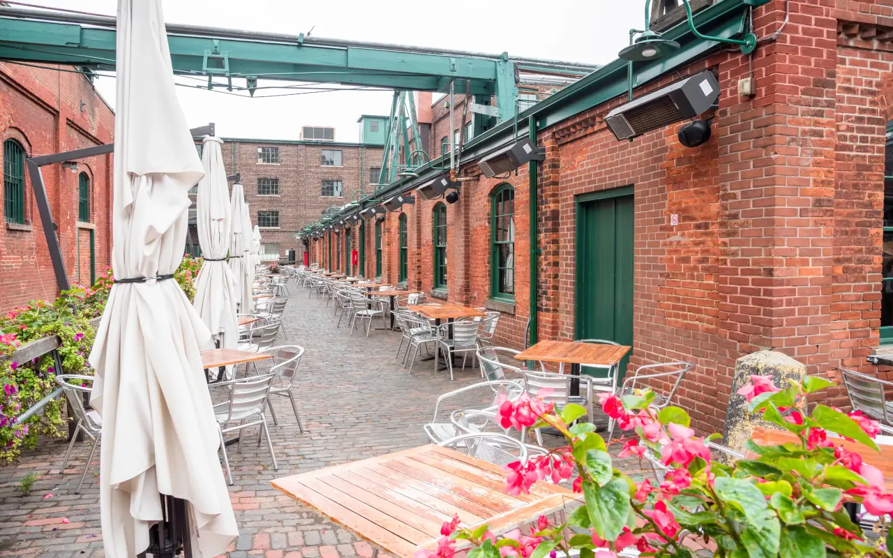 Outdoor dining area with tables under umbrellas and brick buildings