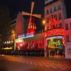 A vibrant image of Moulin Rouge, the iconic Parisian cabaret, with its red windmill and lively atmosphere