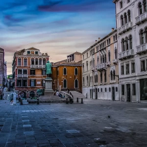 Aerial view of the bustling Piazze Venezia in daytime, showcasing the historic architecture and lively atmosphere