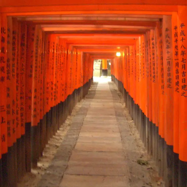 A stunning view of Fushimi Inari Taisha, the iconic Japanese Shinto shrine with vibrant orange torii gates and lush greenery surrounding it