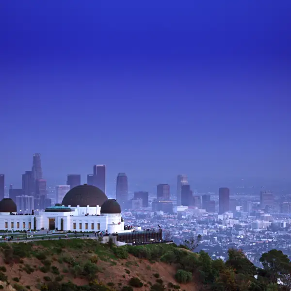 A stunning view of Griffith Observatory, an iconic Los Angeles landmark, situated atop a hill with a beautiful cityscape backdrop