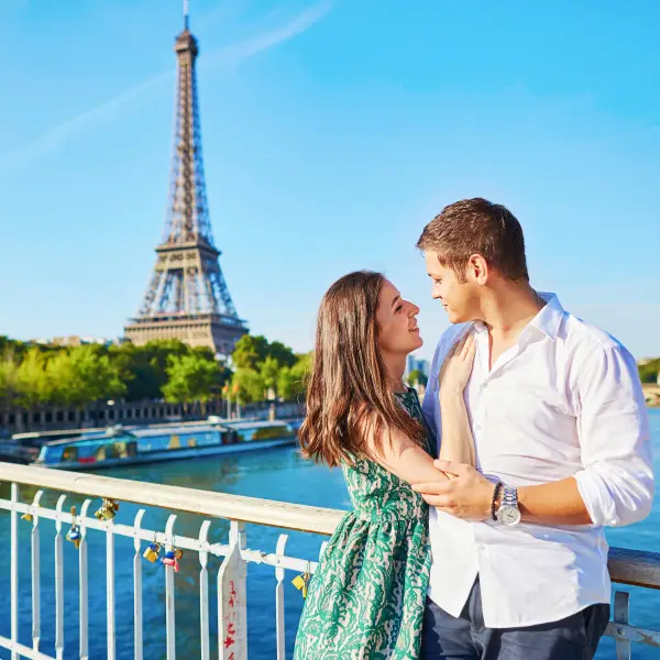 Romantic couple enjoying a leisurely walk along the Seine River, with the Eiffel Tower in the background